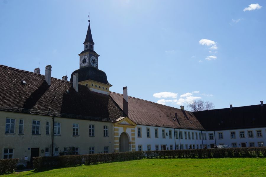 Ansicht der barocken Schlossanlage Schleißheim in Oberschleißheim bei München, mit dem Uhrturm und blauen Himmel.