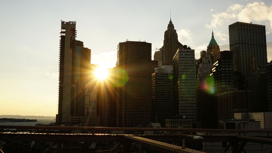 Sonnenuntergang über den Wolkenkratzern von New York City mit strahlendem Licht zwischen den Gebäuden.