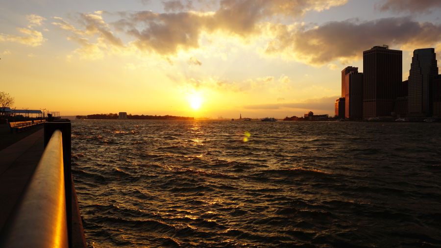 Sonnenuntergang über dem East River in New York City, mit Blick auf die skyline und Wolkenkratzer im Hintergrund.
