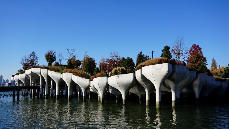 Eine moderne Architekturstruktur mit Pflanzen, die aus dem Wasser ragt und einen kleinen Park auf einem Pier darstellt.