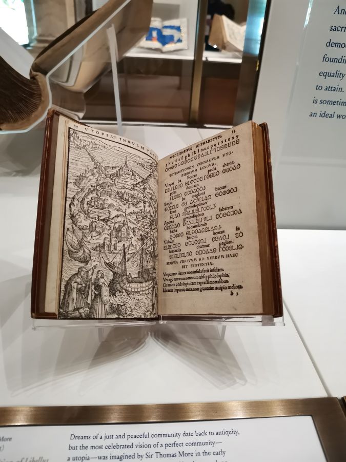 Ein aufgeschlagenes Buch mit einer detaillierten Illustration und Text, das möglicherweise ein historisches Werk oder eine Beschreibung einer idealen Gemeinschaft darstellt.