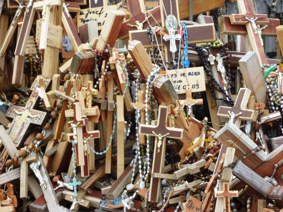 Eine Vielzahl von Holz- und Metallkreuzen, einige mit Perlen und religiösen Symbolen, die dicht beieinander stehen.