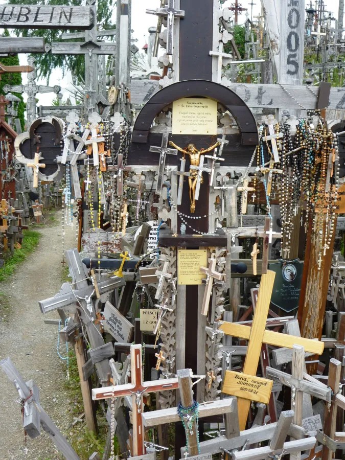 Detailansicht des Berges der Kreuze mit zahlreichen Holzkreuzen, einer zentralen großen Kreuz und religiösen Gegenständen, die umgeben sind von weiteren kleineren Kreuzen.