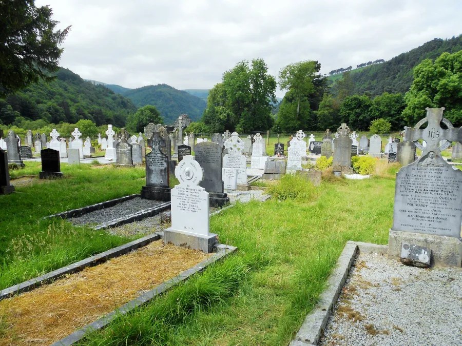 Gräberfeld im Glendalough, Wicklow Mountains Nationalpark, umgeben von Bergen und Bäumen.