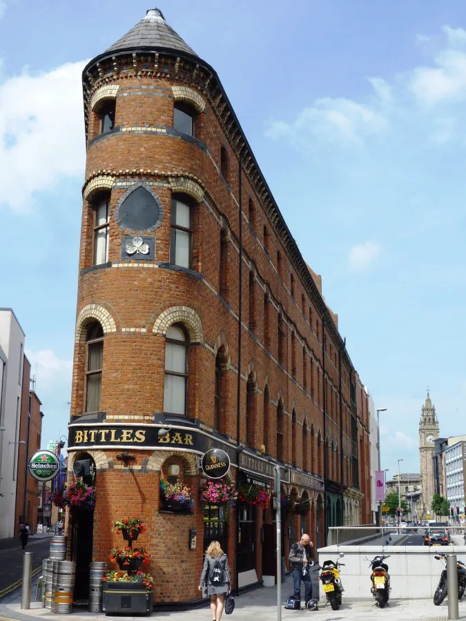 Blick auf das historische Bittles Bar in Belfast, Nordirland, mit dekorativen Blumen und dem charakteristischen roten Ziegelsteinbau.
