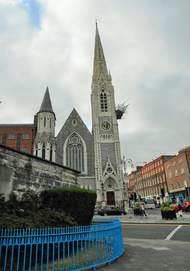 Ein historisches Gebäude mit einem hohen, spitzen Turm und einer charakteristischen Fassade in einer Stadtumgebung.