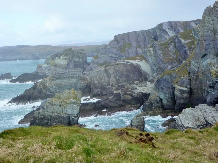 Küstenlandschaft mit Felsen und grünen Wiesen an der Küste Irlands