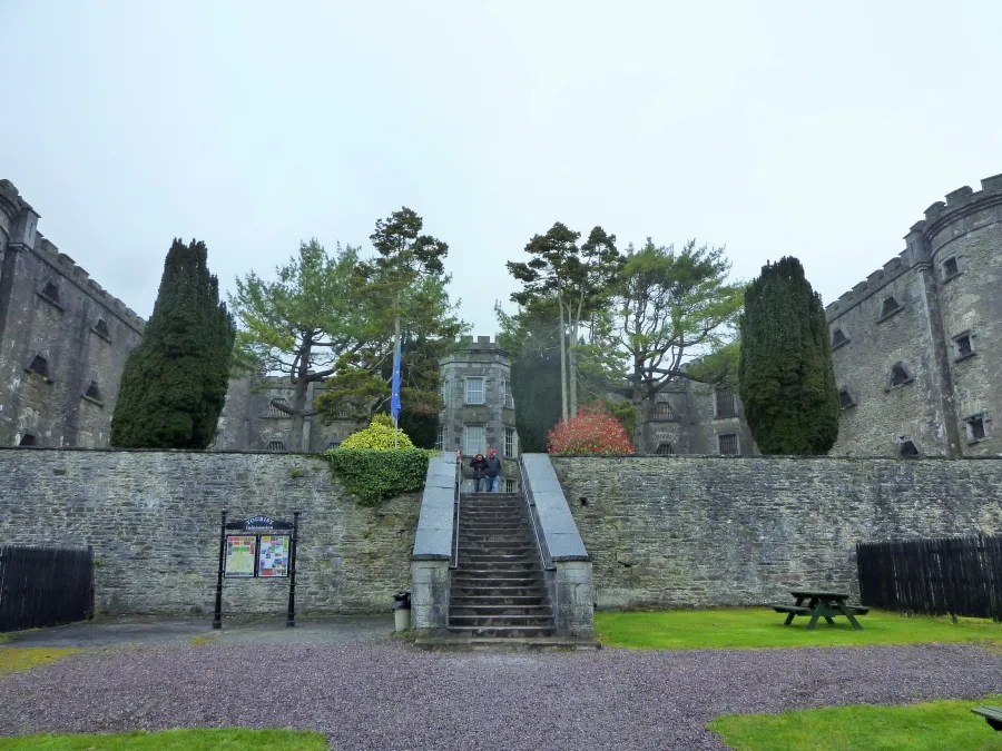 Eingang zu einem historischen Gefängnis mit Stufen und Bäumen im Hintergrund.