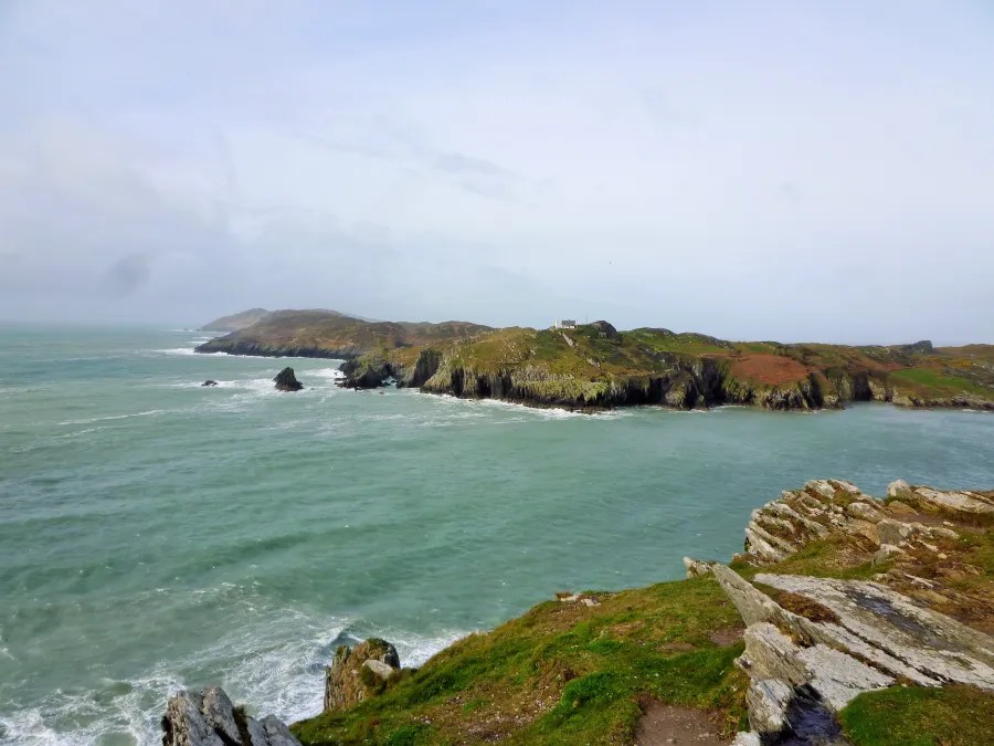 Blick auf die Küste von Irland mit sanften Hügeln und rauschenden Wellen des Atlantiks.