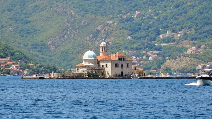 Eine wunderschöne Ansicht einer kleinen Insel mit einem historischen Gebäude, umgeben von Wasser und sanften Hügeln im Hintergrund.