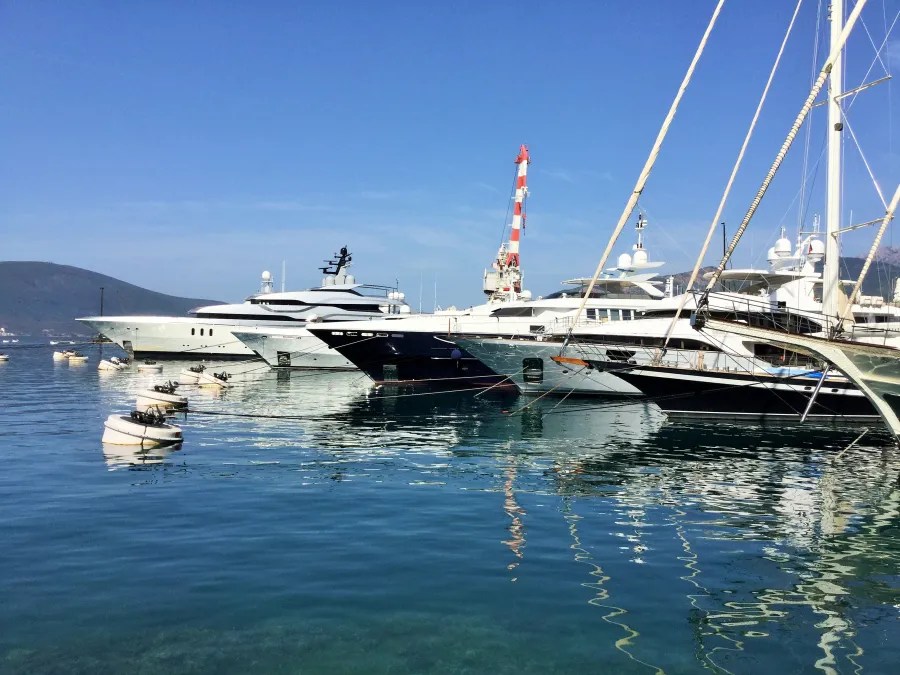 Luxuriöse Yachten im Hafen von Tivat, Montenegro, bei klarem blauen Himmel und ruhigem Wasser.