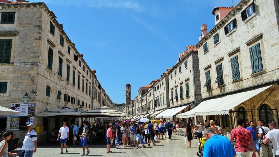 Ein belebter Platz in Dubrovnik, Kroatien, mit historischen Gebäuden und vielen Touristen an einem sonnigen Tag.