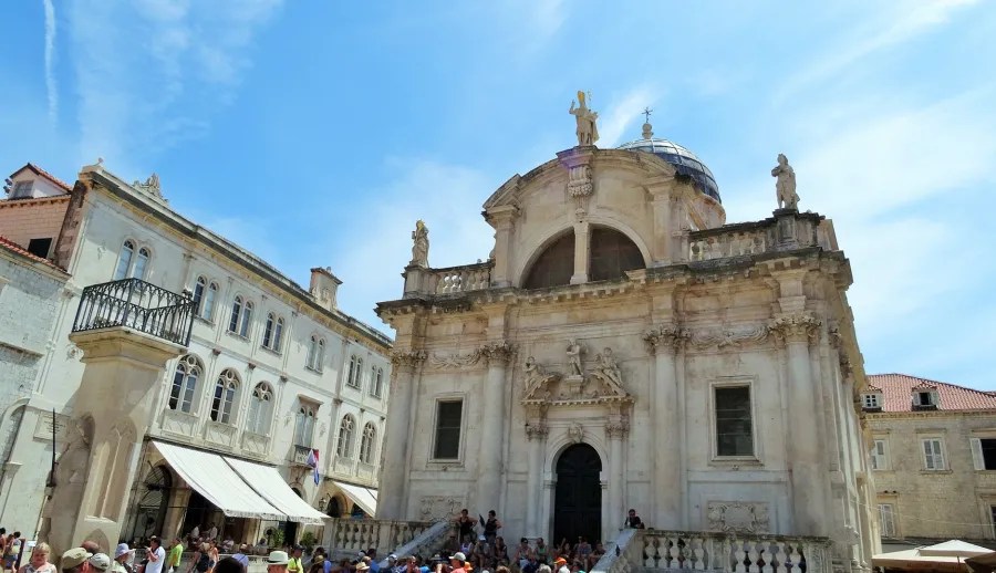 Die Kirche von St. Blaise in Dubrovnik, Kroatien, mit repräsentativer Fassade und zahlreichen Touristen vor dem Gebäude, unter einem blauen Himmel.