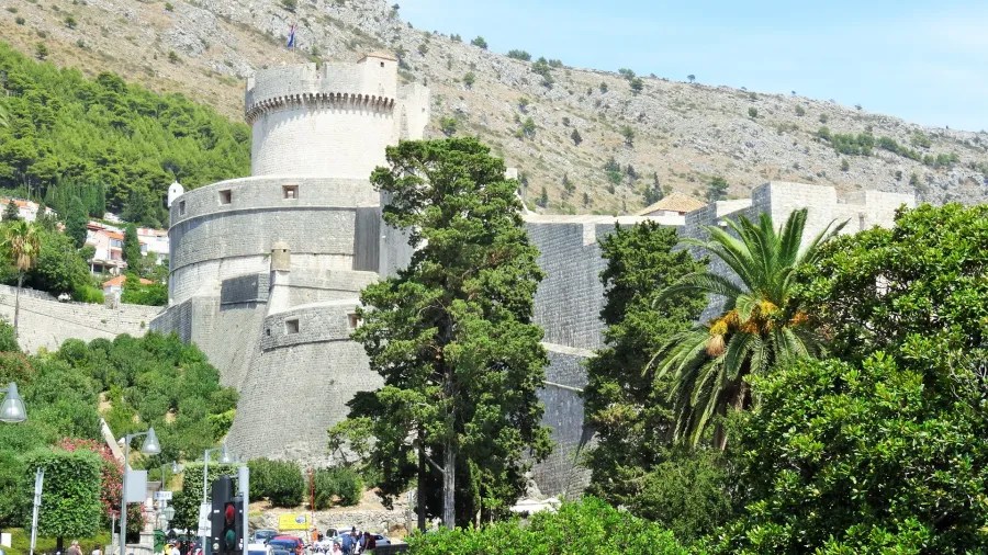 Historische Festung in Dubrovnik, Kroatien, umgeben von grünen Pflanzen und Bergen.