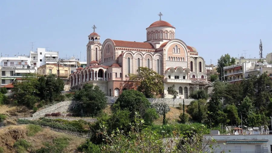 Eine beeindruckende Kirche in Thessaloniki, Griechenland, umgeben von Bäumen und Stadthäusern.