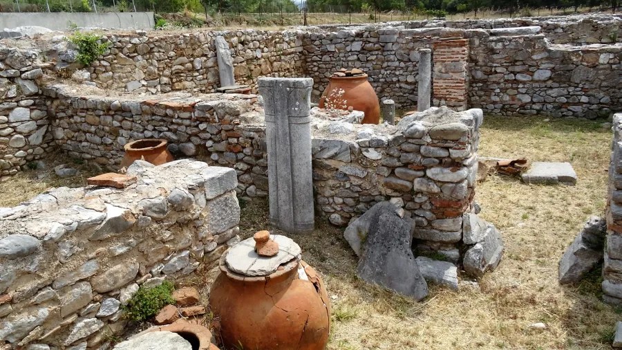 Archäologische Ruinen mit Steinen und Keramiktöpfen in einer alten Siedlung.