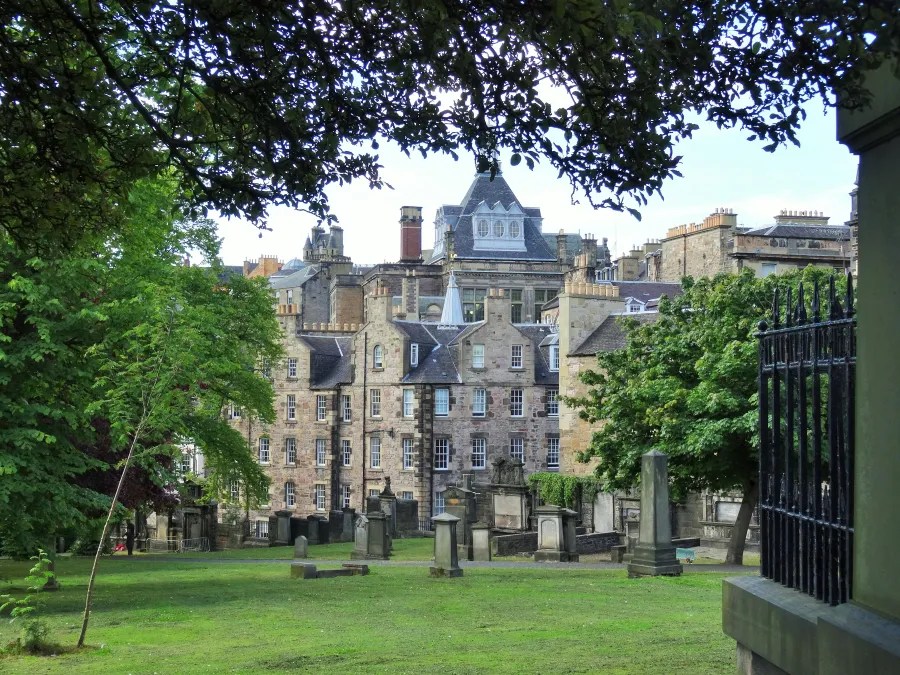 Blick auf historische Gebäude in Edinburgh, umgeben von Bäumen und einem kleinen Friedhof.
