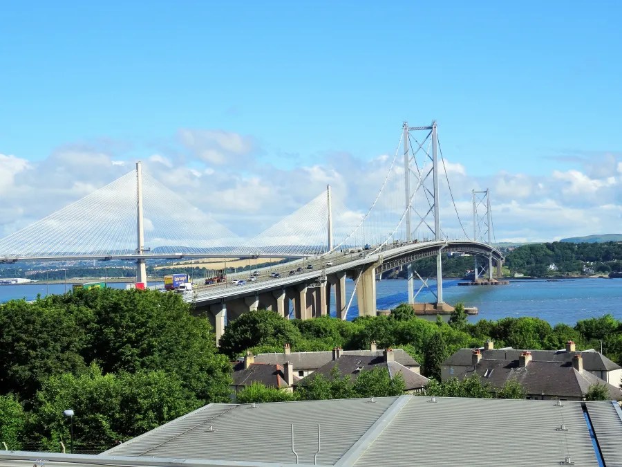 Die Forth Road Bridge, ein beeindruckendes Bauwerk, überquert den Firth of Forth mit einer klaren blauen Himmel und grünem Hintergrund.