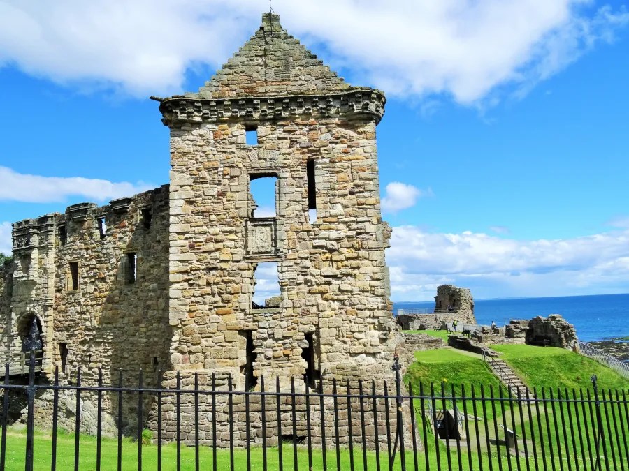 Die Ruine eines historischen Gebäudes mit einer einzelstehenden Turmstruktur und Blick auf das Meer unter einem klaren blauen Himmel.