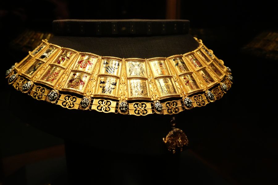 Eine goldene Halskette mit bunten, bemalten Medaillons, ausgestellt in einem Museum.