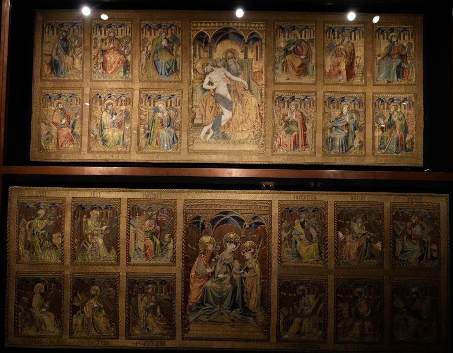 Religious artwork featuring a series of illuminated panels with biblical figures and scenes in vibrant colors, displayed in a museum setting.