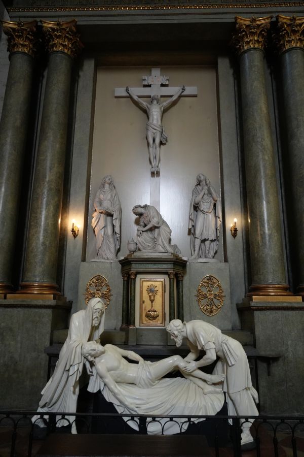 Skulptur eines Pietá-Motivs in der Kapuzinergruft, mit einer Darstellung von Maria und Jesus, umgeben von Säulen und Figuren im Hintergrund.