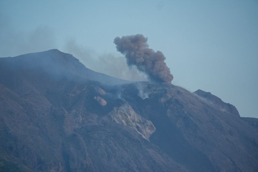 Der Vulkan Stromboli mit rauchenden Ausbrüchen vor einem klaren Himmel.