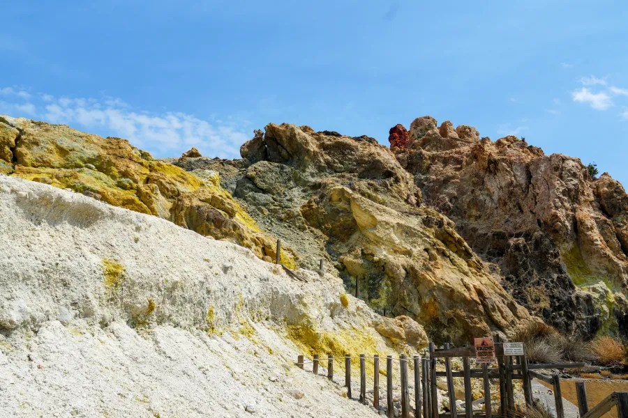 Bunte Steinklippen mit gelben und orangefarbenen Mineralien unter einem blauen Himmel auf der Insel Vulcano.