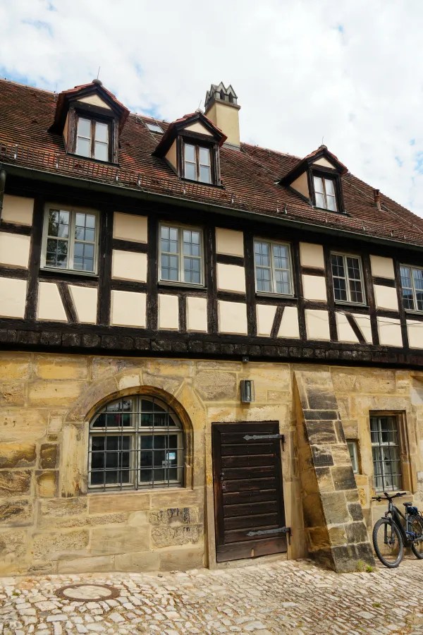 Fachwerkhaus mit steingemauerter Fassade und mehreren Fenstern, unter einem rotziegelnen Dach, gelegen in einer malerischen Altstadt.
