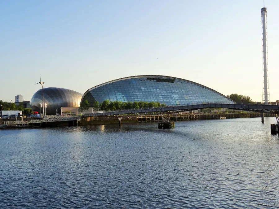 Blick auf die moderne Architektur am Clyde in Glasgow, Schottland, mit dem Wasser im Vordergrund und einem klaren Himmel im Hintergrund.