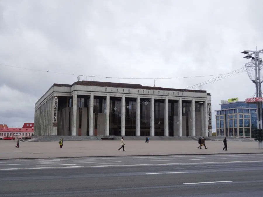 Blick auf das Gebäude des Palasts der Unabhängigkeit in Minsk, umgeben von einem weitläufigen Platz und unter einem bewölkten Himmel.