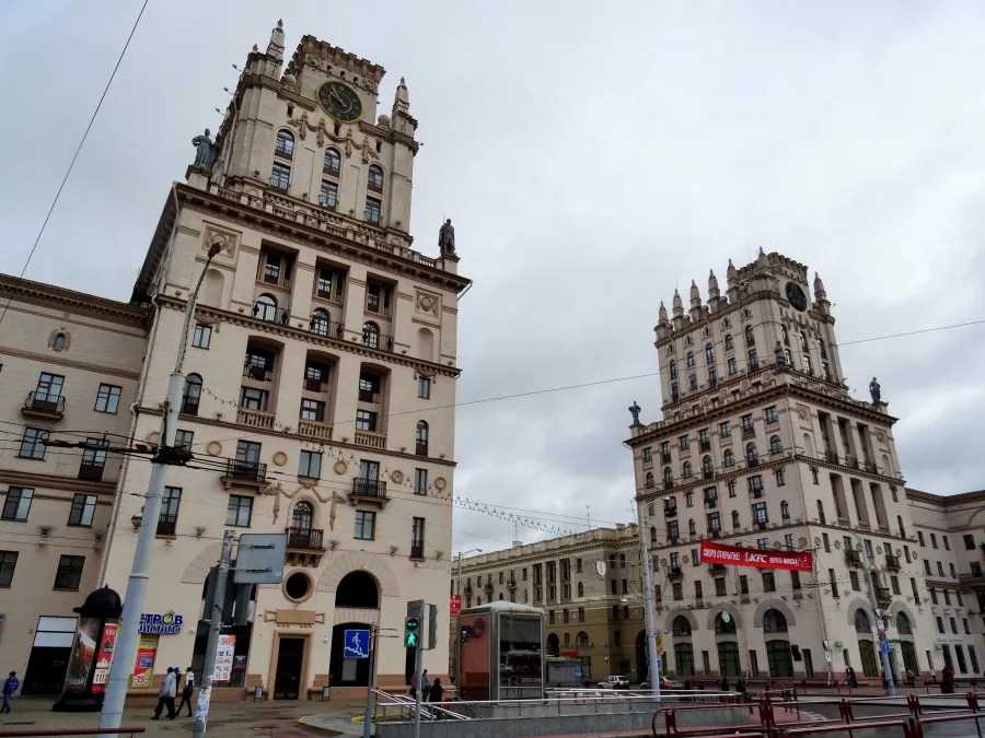 Zwei historisch-elegante Gebäude in Minsk, mit auffälliger Architektur, Wolken am Himmel und einer urbanen Umgebung.