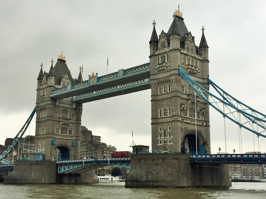 Die Tower Bridge in London an einem grauen und regnerischen Tag, mit einem roten Bus auf der Brücke.