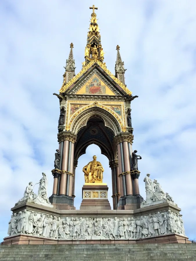 Ein goldener Sockel mit einer Statue von Prince Albert, umgeben von kunstvollen Skulpturen und einem gotischen Denkmal im Albert Memorial in London.