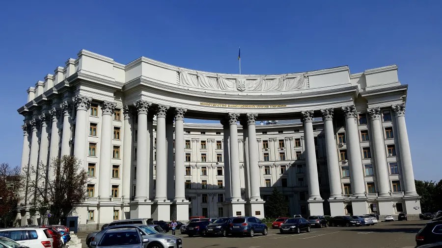 Das Gebäude des ukrainischen Außenministeriums unter blauem Himmel mit weißen Säulen und einer Fahne auf dem Dach.
