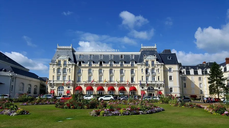 Das Grand Hotel in Cabourg, umgeben von bunten Blumen im Vordergrund und unter einem klaren blauen Himmel.
