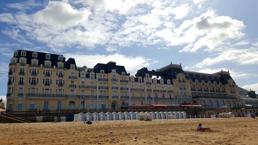 Luxuriöses Grand Hotel an der Küste von Cabourg mit einer eleganten Fassade und einem goldenen Sandstrand im Vordergrund.