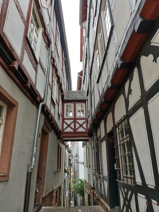 Engpass zwischen historischen Fachwerkhäusern in Marburg mit einem überdachten Gehweg und einer gemütlichen Atmosphäre.