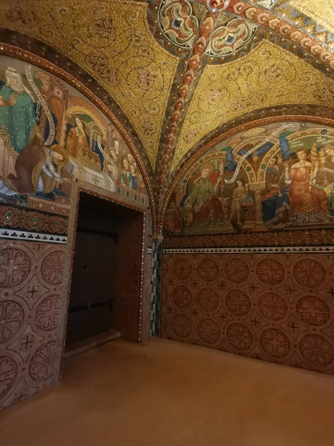 Detailed view of an intricately decorated room featuring ornate ceiling and wall frescoes, showcasing historical figures and patterns.