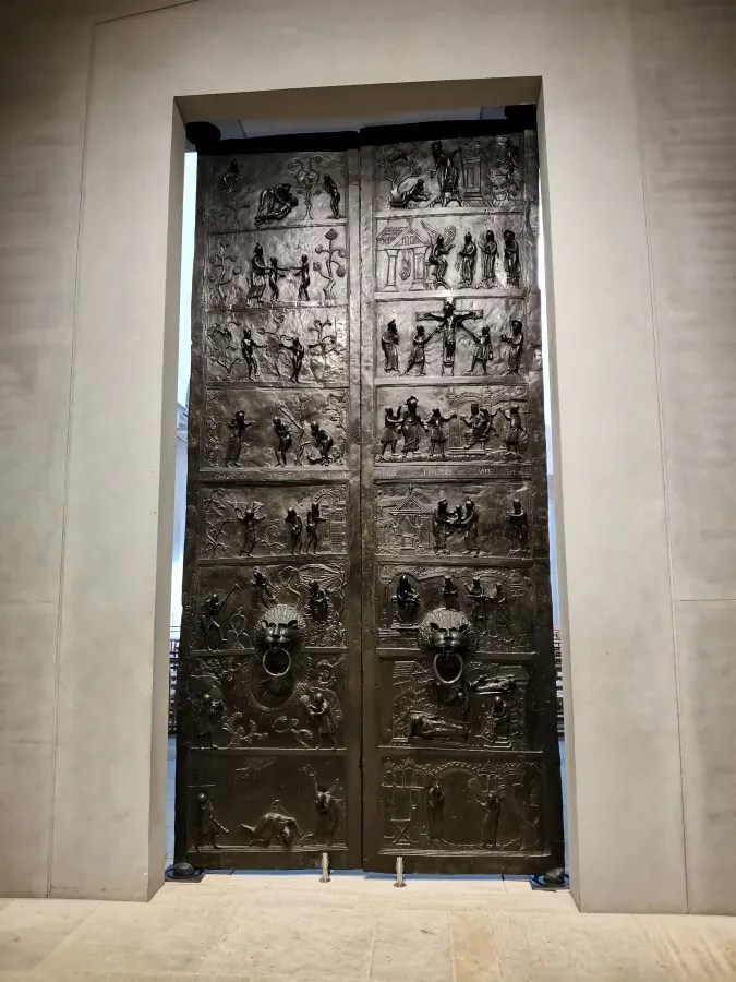 Bronze door with intricate relief sculptures depicting various historical and mythological scenes.