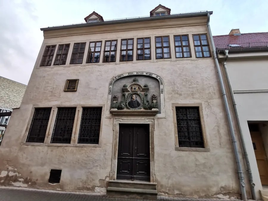 Außenansicht eines historischen Gebäudes mit einem bemerkenswerten Portal und Fenstern, das eine Erinnerung an Martin Luther darstellt.