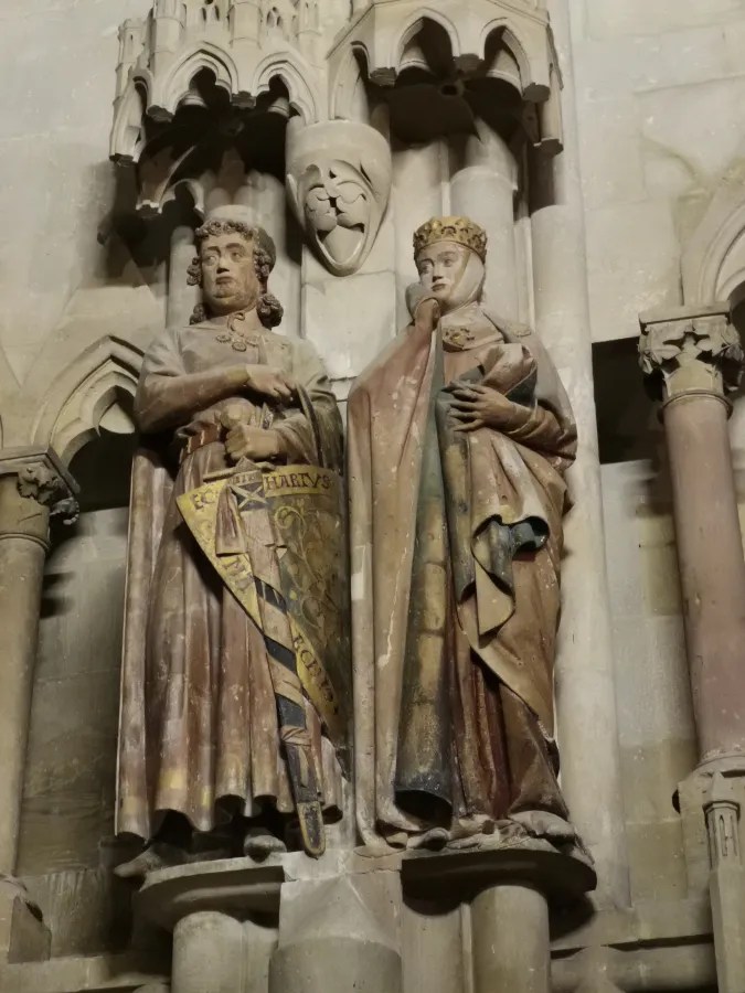 Skulpturen von zwei heiligen Figuren in historischer Kleidung, die an einer Wand in einem Gebäude angebracht sind.