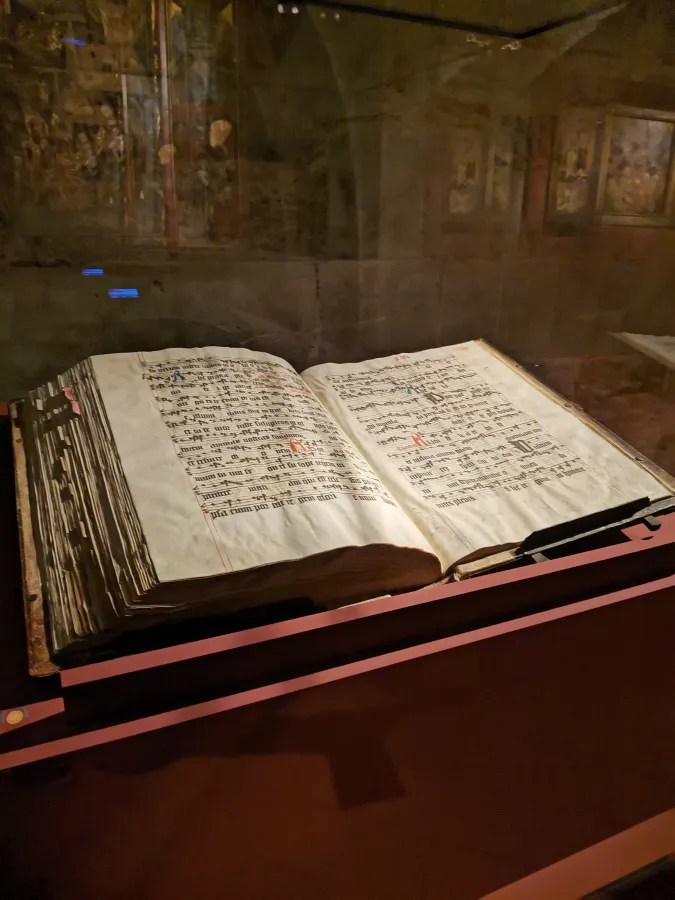 Ein aufgeschlagenes historisches Buch in einem Glaskasten, das handschriftliche Notizen und musikalische Notation zeigt.