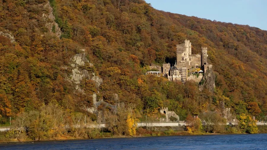 Rheinfels Castle situated on a hillside, surrounded by autumn foliage and overlooking the Rhine River.