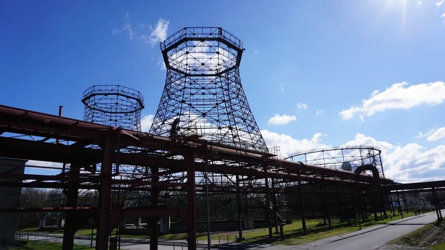 Stahlkonstruktionen und Rohrleitungen auf dem Areal der Zeche Zollverein unter einem strahlend blauen Himmel.