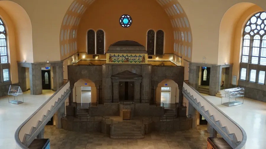 Innenansicht der Alten Synagoge in Essen mit kunstvoll gestalteten Fenstern und einem zentralen Bereich, der zum Gebet genutzt wird.