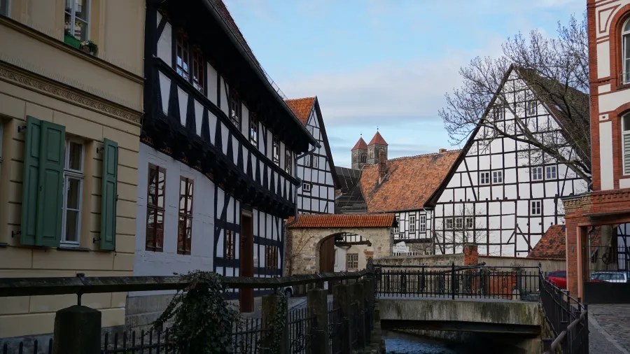 A scenic view of traditional German architecture featuring half-timbered houses along a canal, with a clear blue sky in the background.