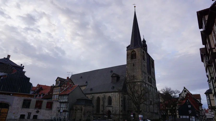 A historic church with a tall spire, surrounded by traditional German buildings and a cloudy sky.