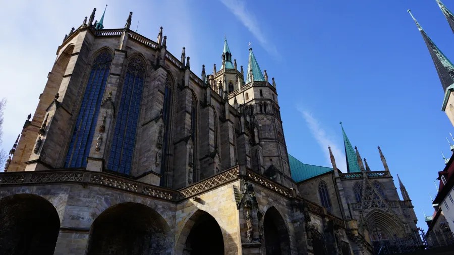 View of a historic cathedral featuring ornate architecture, tall spires, and detailed stonework under a clear blue sky.