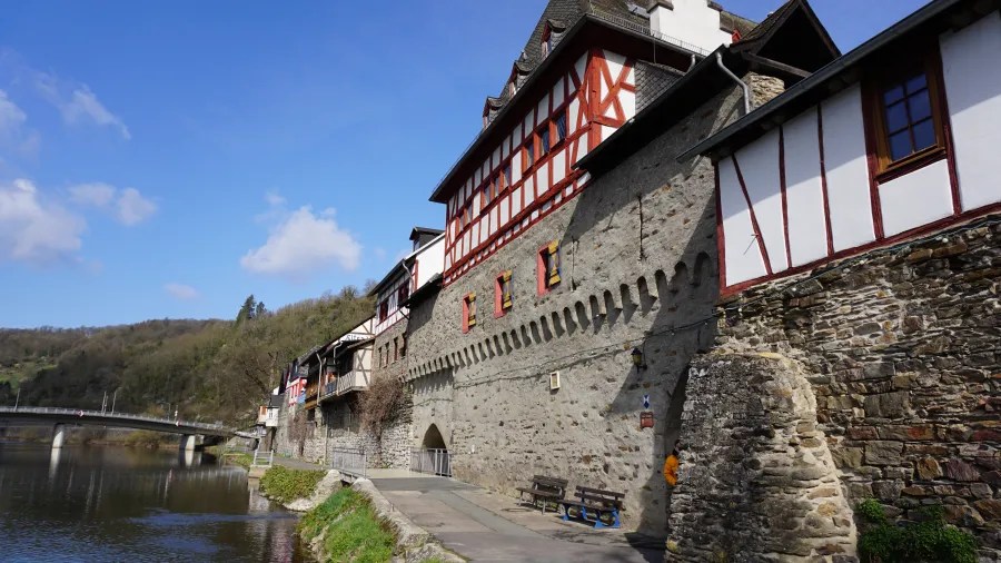 Ansicht eines historischen Fachwerkhauses am Ufer der Lahn in Nassau, Deutschland, mit blauem Himmel und vereinzelten Wolken im Hintergrund.